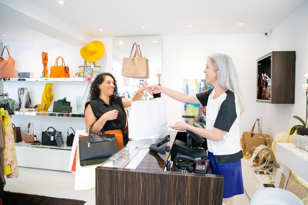 clothes shop cashier giving paper bag to customer